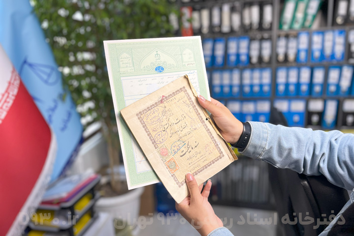 تصویر سند تکبرگ و دفترچهای در دست فرد، مربوط به ثبت اسناد و املاک ایران